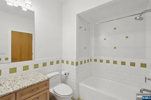 a bathroom with a granite countertop bathtub sink vanity mirror and toilet