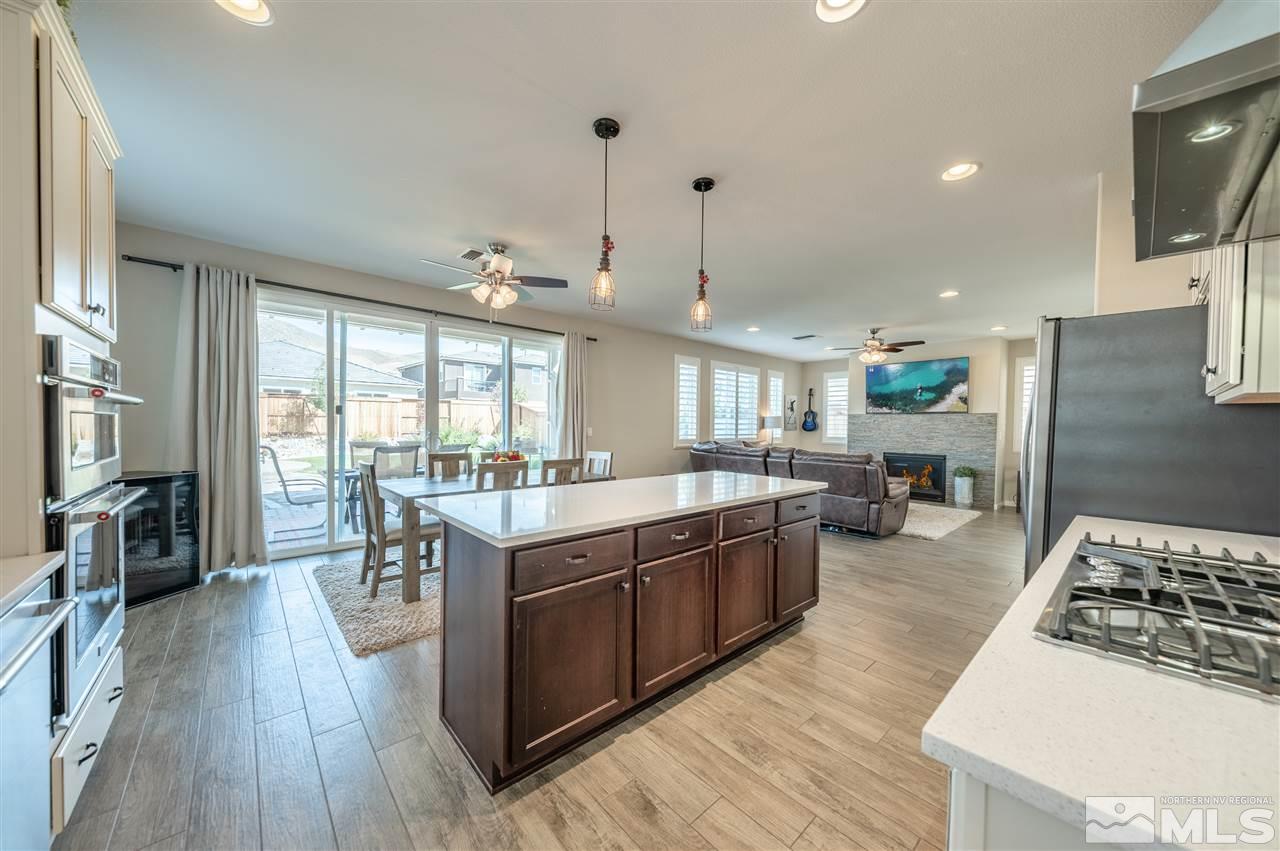 2935 Bonfire Lane Reno, NV 89521 - Photo 15 of 39 a large kitchen with stainless steel appliances a stove a sink dishwasher a dining table and chairs with wooden floor