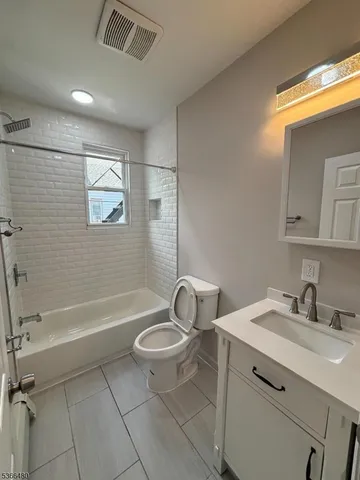 a bathroom with a granite countertop sink toilet a mirror and bathtub