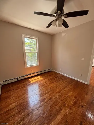 an empty room with wooden floor fan and windows
