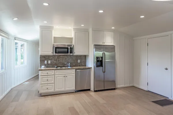 a hall with stainless steel appliances granite countertop a stove a sink and a refrigerator