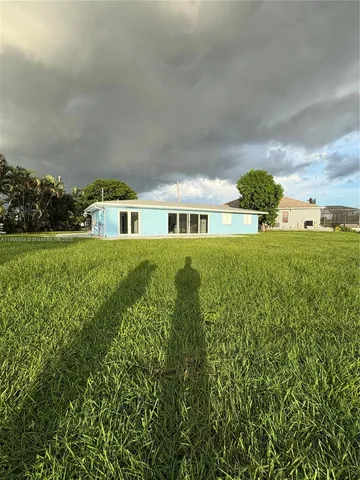 a view of a big yard with plants and large trees