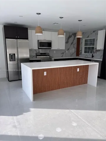 a kitchen with stainless steel appliances a sink a stove a microwave a sink a refrigerator and cabinets