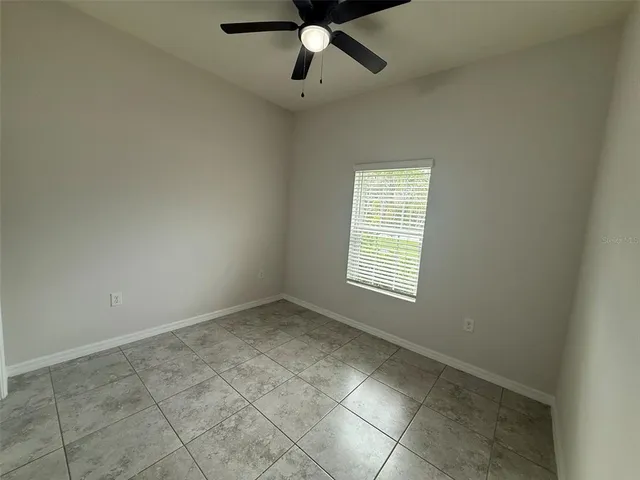 an empty room with a ceiling fan and window
