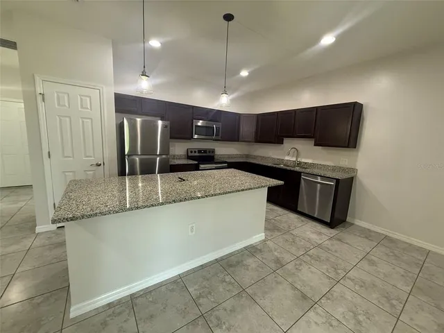 a kitchen with granite countertop a refrigerator and a sink