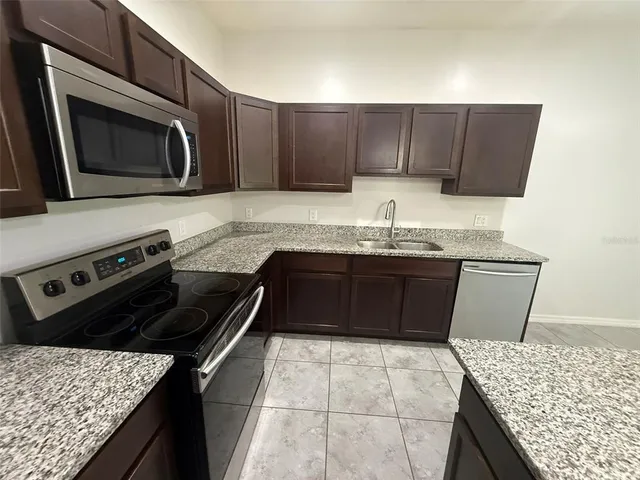a kitchen with granite countertop cabinets a sink and a stove
