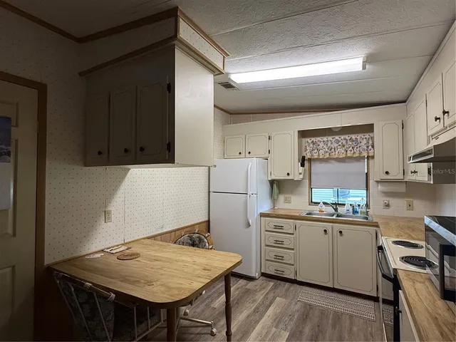 a kitchen with a table chairs refrigerator and cabinets