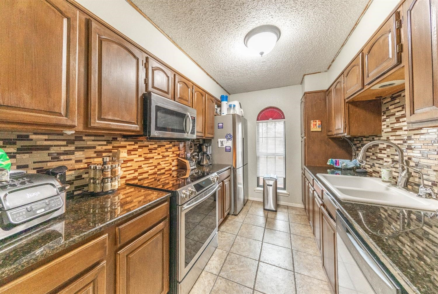 5722 2nd Place Lubbock, TX 79416 - Photo 6 of 21 a kitchen with stainless steel appliances granite countertop a stove and cabinets