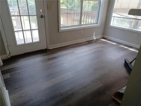 an empty room with wooden floor and windows