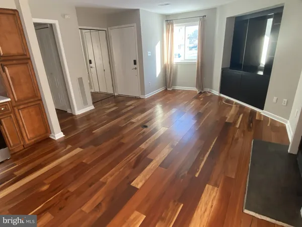a view of an empty room with wooden floor and a window