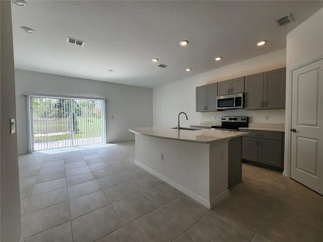 a kitchen with kitchen island granite countertop a stove sink and cabinets