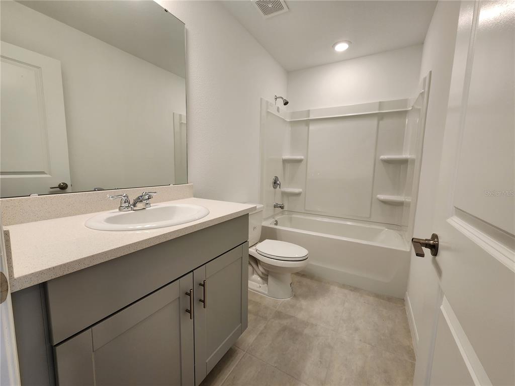 2620 Penguin Boulevard Davenport, FL 33837 - Photo 9 of 14 a bathroom with a granite countertop sink toilet a shower and a mirror