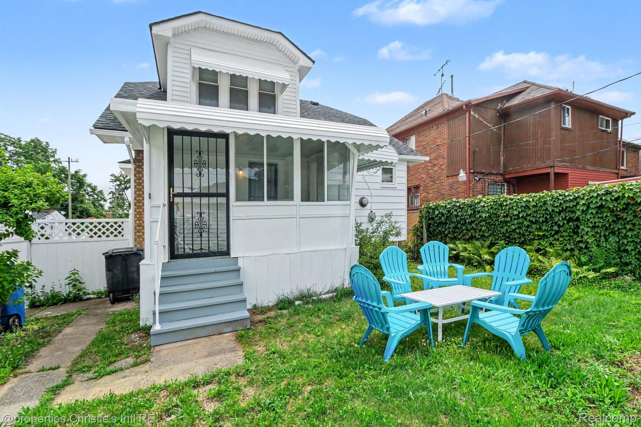 18315 Prairie Street Detroit, MI 48221 - Photo 15 of 16 White siding exterior featuring a screened-in porch with awnings and a separate upper-level window with awning