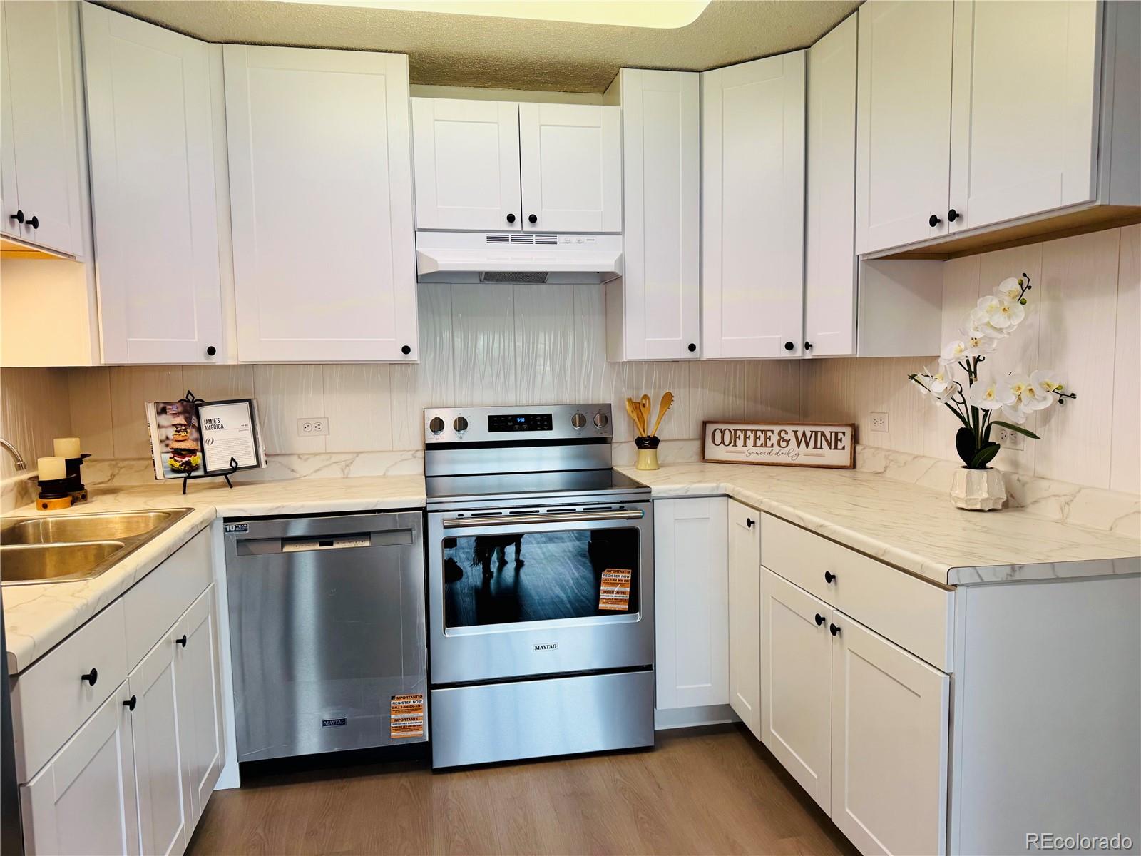 755 South Alton Way, Unit 12C Denver, CO 80247 - Photo 1 of 12 a kitchen with granite countertop white cabinets and white appliances