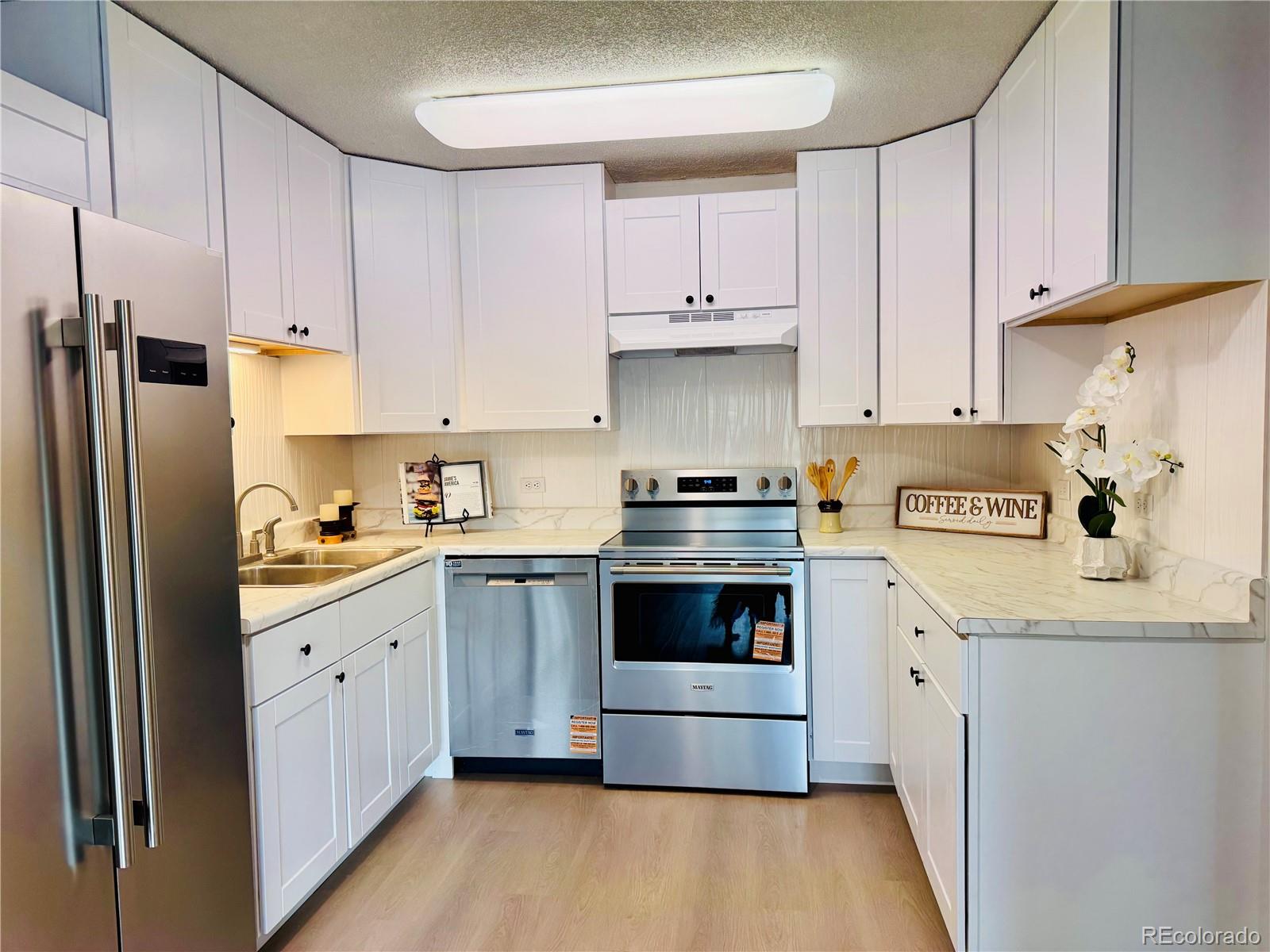 755 South Alton Way, Unit 12C Denver, CO 80247 - Photo 3 of 12 a kitchen with stainless steel appliances granite countertop a refrigerator sink and white cabinets