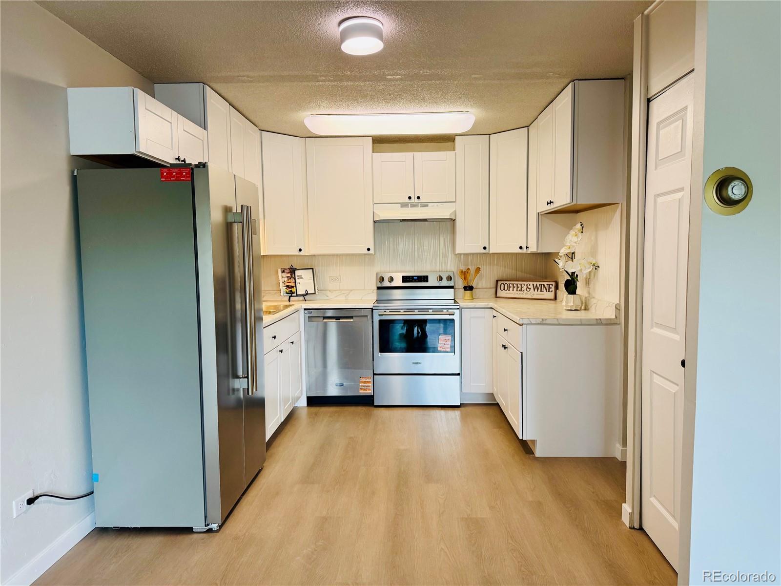 755 South Alton Way, Unit 12C Denver, CO 80247 - Photo 4 of 12 a kitchen with a sink a refrigerator and white cabinets