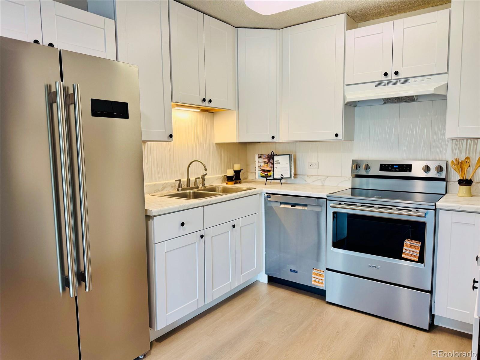 755 South Alton Way, Unit 12C Denver, CO 80247 - Photo 5 of 12 a kitchen with stainless steel appliances white cabinets and a refrigerator