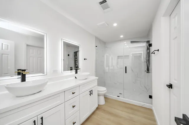 a bathroom with a double vanity sink toilet and shower