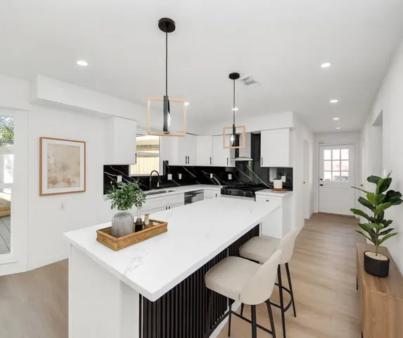 a kitchen with a table chairs sink and white cabinets