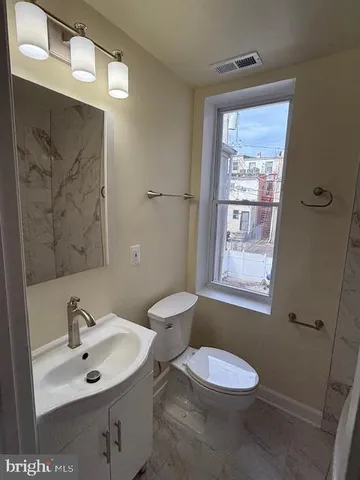 a bathroom with a toilet a sink a mirror and a window