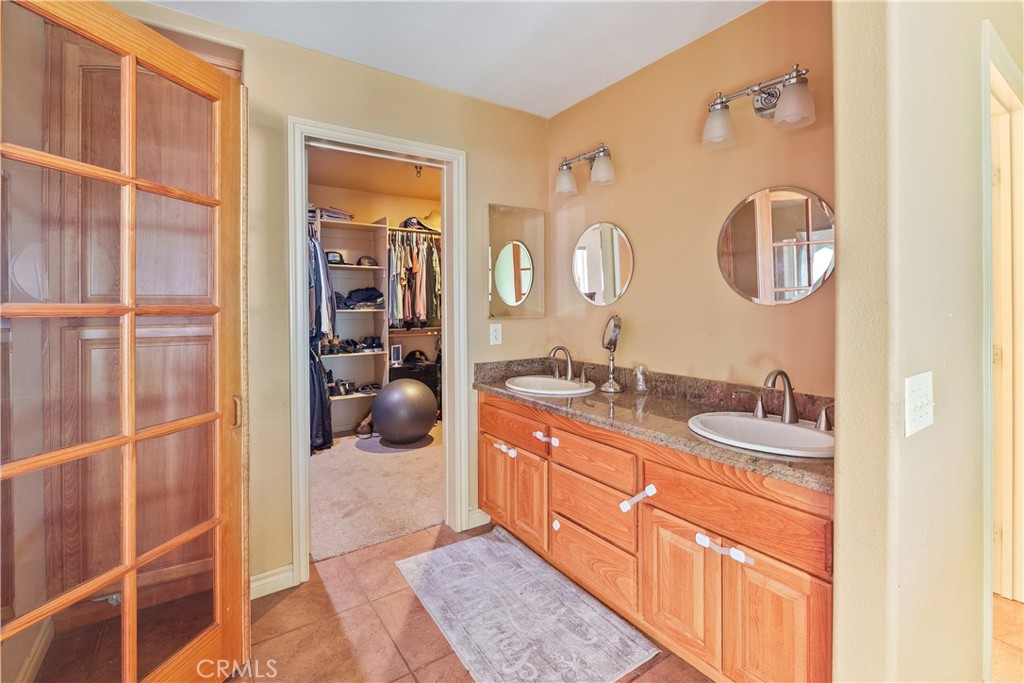 23053 Roundup Way Apple Valley, CA 92308 - Photo 25 of 46 a en suite bathroom with a double vanity sink and a mirror