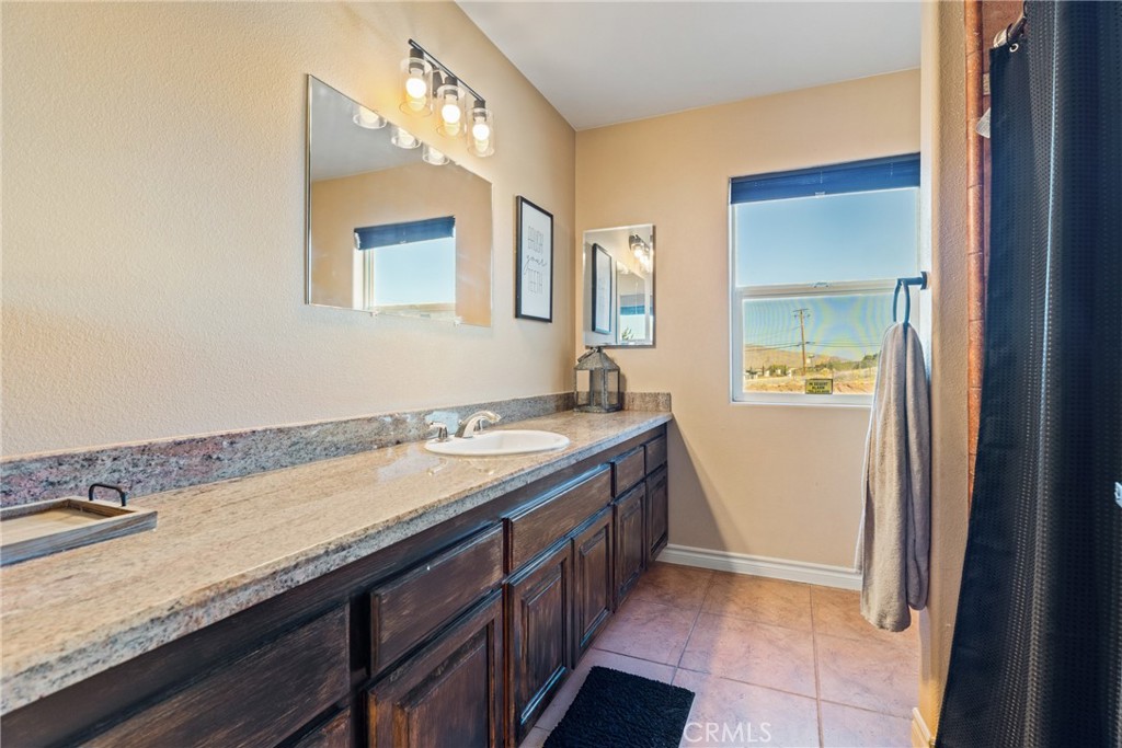 23053 Roundup Way Apple Valley, CA 92308 - Photo 32 of 46 a bathroom with a granite countertop sink and a mirror