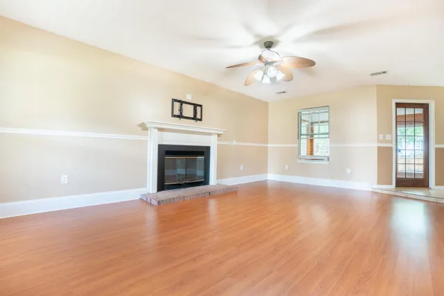 a view of an empty room with window and wooden floor