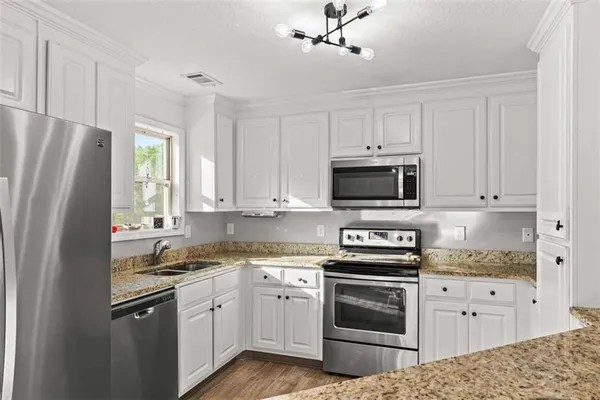 a kitchen with stainless steel appliances white cabinets and a stove a refrigerator with wooden floor