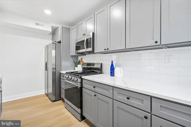 a kitchen with stainless steel appliances granite countertop white cabinets and a stove