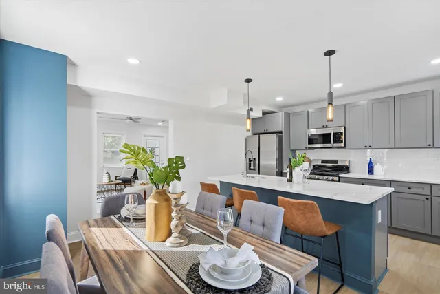 a kitchen with stainless steel appliances kitchen island granite countertop a dining table chairs and white cabinets