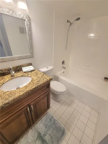 a bathroom with a granite countertop toilet a sink a mirror and bathtub