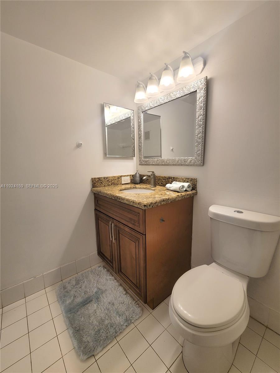 2133 Renaissance Boulevard, Unit 306 Miramar, FL 33025 - Photo 20 of 32 a bathroom with a granite countertop toilet a sink and a mirror