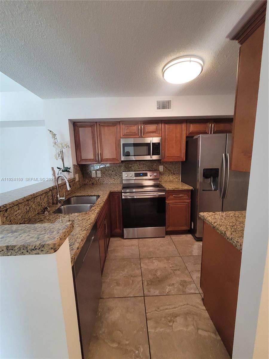 2133 Renaissance Boulevard, Unit 306 Miramar, FL 33025 - Photo 2 of 32 a large kitchen with granite countertop a stove top oven a sink dishwasher and a refrigerator
