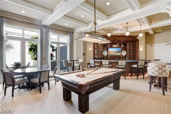 a room with lots of tables a chandelier and pool table