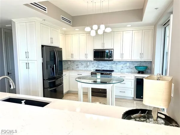 a kitchen with a refrigerator a stove a sink and white cabinets with wooden floor