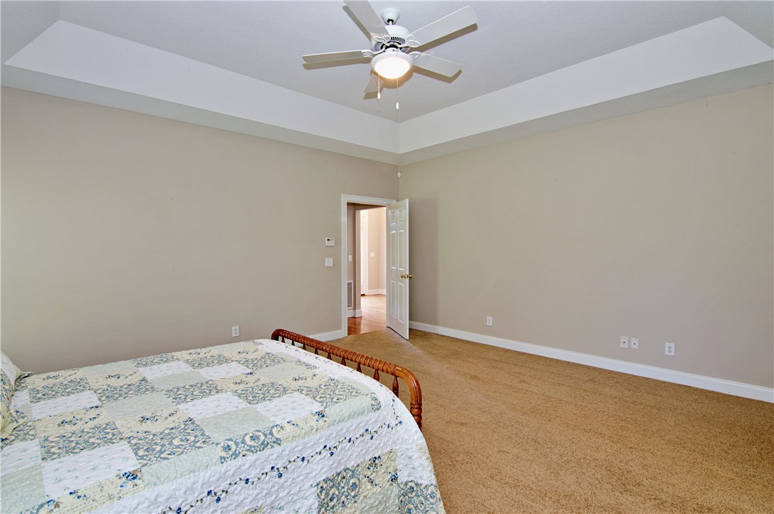 7893 Athens Road Carnesville, GA 30521 - Photo 18 of 50 This spacious bedroom features a ceiling fan, tray ceilings, and comfortable carpeting.