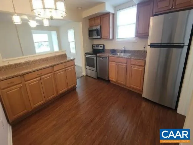 a kitchen with stainless steel appliances granite countertop a refrigerator a sink dishwasher a stove with wooden floor and cabinets