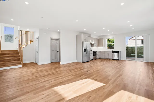 a view of an empty room with wooden floor and stairs