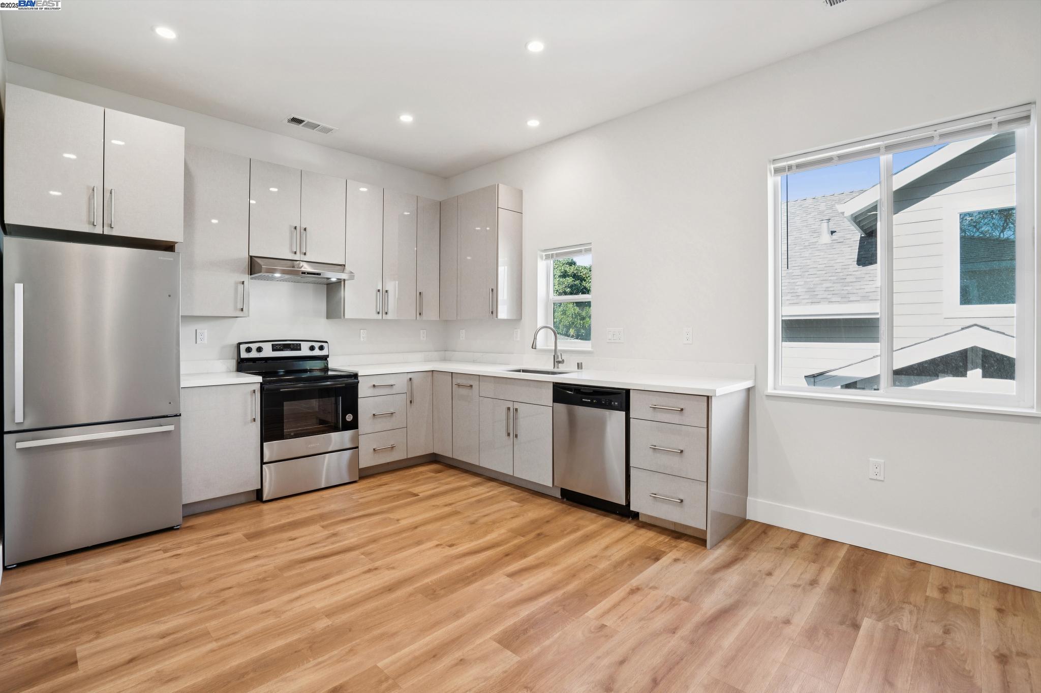 882 61st Street Oakland, CA 94608 - Photo 4 of 51 a kitchen with granite countertop a refrigerator oven a sink dishwasher and white cabinets with wooden floor