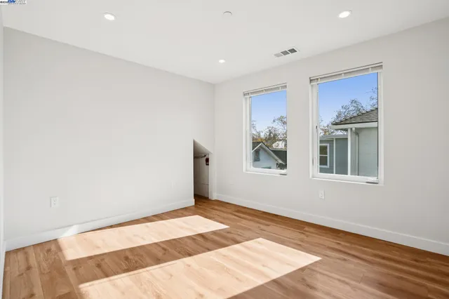 a view of an empty room with wooden floor and window