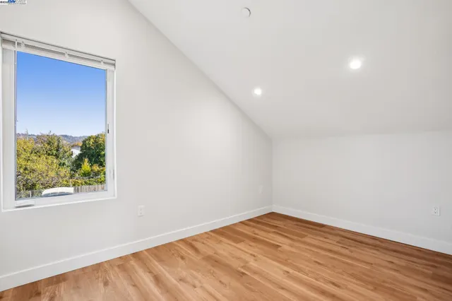 a view of a hallway with wooden floor and a bathroom