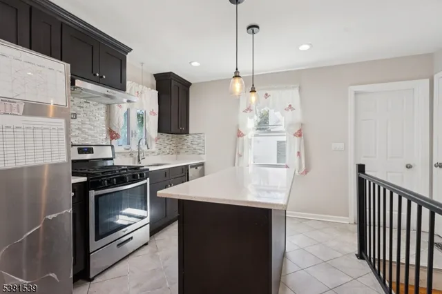 a kitchen with stainless steel appliances kitchen island granite countertop a stove a sink and a refrigerator