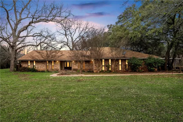 a view of a big house with a big yard and large trees