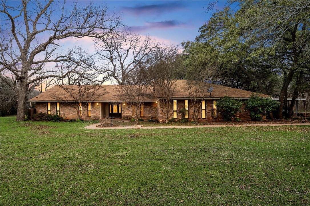 a view of a big house with a big yard and large trees
