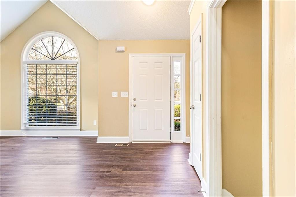 7810 Wynfield Circle Cumming, GA 30040 - Photo 7 of 47 an empty room with wooden floor chandelier and windows