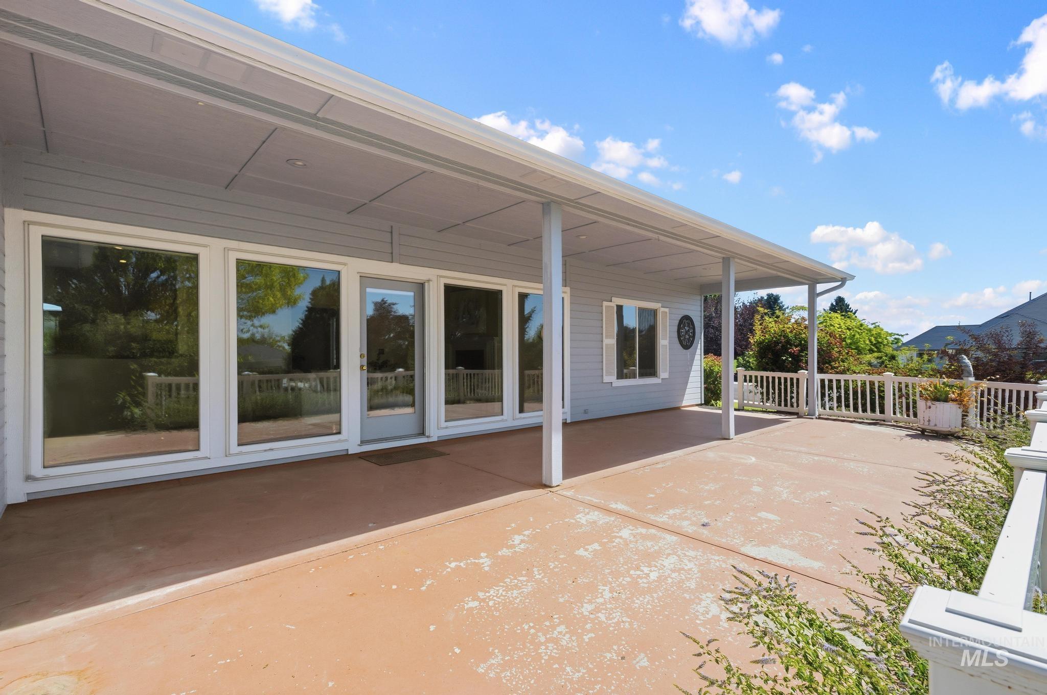 15181 Drury Way Caldwell, ID 83607 - Photo 31 of 49 Expansive covered patio featuring a concrete surface, multiple large windows, a glass-paned door, white railing, and exterior siding