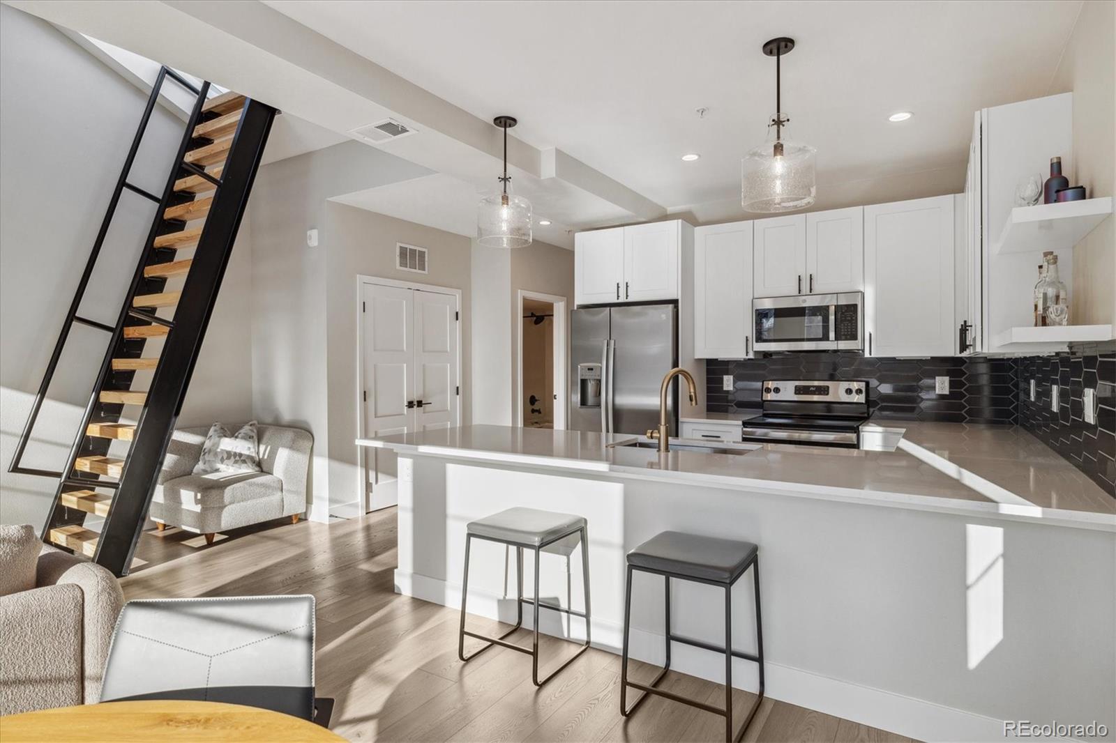 1401 Jackson Street, Unit 204 Golden, CO 80401 - Photo 11 of 26 a kitchen with stainless steel appliances a refrigerator a stove a sink dishwasher and white cabinets with wooden floor