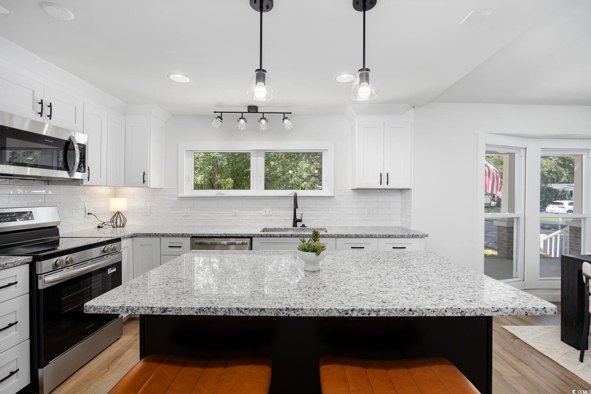 983 South Marlin Circle Murrells Inlet, SC 29576 - Photo 9 of 40 Kitchen featuring stainless steel appliances, a breakfast bar area, decorative backsplash, light wood-type flooring, and recessed lighting