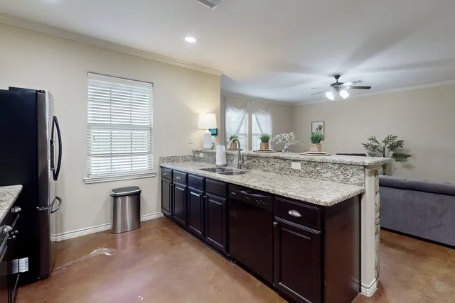a kitchen with granite countertop a sink stainless steel appliances and window