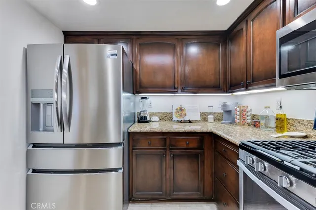a kitchen with stainless steel appliances granite countertop a refrigerator a sink a stove and cabinets